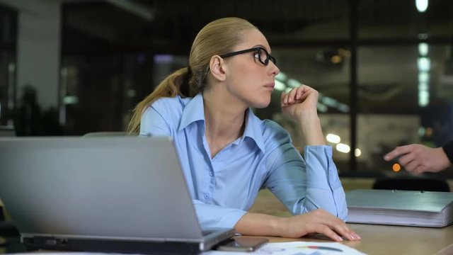 Woman gets more paperwork at end of working day, closing folder to avoid job