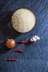 Ingredients for making pilaf, rice, onion and garlic on a dark background. Vertical orientation