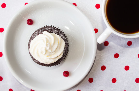 cupcake with cheese cream, red berries and a cap of tea