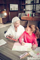 Helpful granny assisting her granddaughter making homework