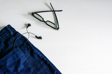 Headphones and glasses in the jeans pocket on a white background