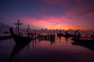 The background of the morning sunrise scenery by the sea, the fishing boats parked in the blurred beauty of the sea breeze that passes through, is the beauty of nature during traveling.