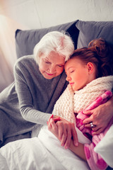 Dark-haired sick girl falling asleep near granny while feeling sick