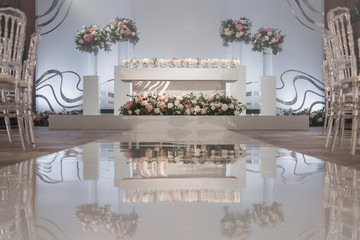 The table of the newlyweds. Small flower arrangements in ball glass vases. Interior of restaurant for wedding dinner, ready for guests. Catering concept.