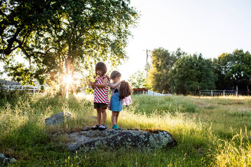 Two young girls exploring and having fun in a open field at sunset.