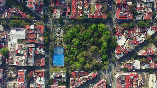 DRONE FLIGHT OVER PARK IN MEXICO CITY RESIDENTIAL AREA. KIDS PLAYGROUND COLORFUL, BLUE BASKETBALL COURT, AND CITY STABLISH