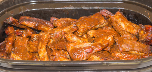 Barbecued Ribs Cot and Placed in a Pan: Freshly cooked barbecue ribs cut and placed in a pan for serving with sauce already applied.
