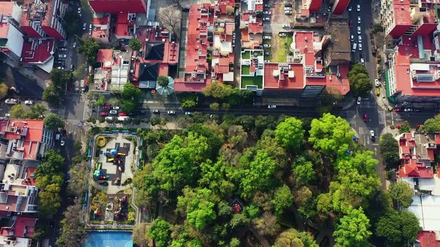 DRONE FLIGHT OVER PARK IN MEXICO CITY RESIDENTIAL AREA. KIDS PLAYGROUND COLORFUL, BLUE BASKETBALL COURT, AND CITY STABLISH