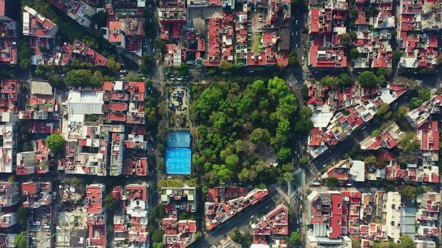 DRONE FLIGHT OVER PARK IN MEXICO CITY RESIDENTIAL AREA. KIDS PLAYGROUND COLORFUL, BLUE BASKETBALL COURT, AND CITY STABLISH