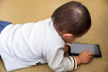 赤ちゃんの男の子ががスマートフォンを持って遊んでいる見ているゲームをしている現代時代