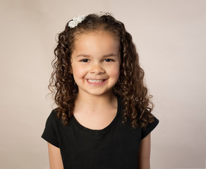 Biracial preschooler with curly brown hair isolated on brown background - 264518529