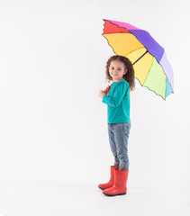 Curly haired little girl with rainbow umbrella and red rain boots