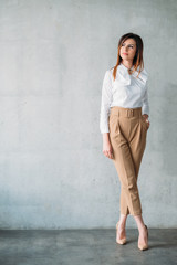 Successful business woman. Smart brunette young lady in formal outfit standing with legs crossed....