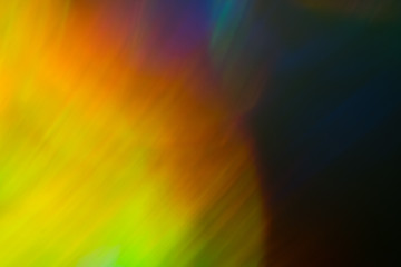 Blurry yellow flare spot on navy blue background. Bokeh effect. Defocused colorful abstract design.