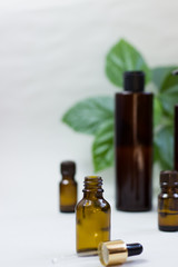 Dark cosmetic bottles and green natural leaves on a light background. Copy space Beauty salon blogger, salon therapy, minimalist concept. The concept of natural environmentally friendly cosmetics.