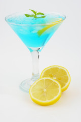 Blue cocktail with lime slice and mint in glass top view isolated on white background