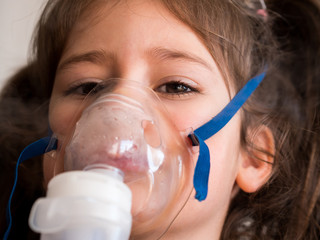 Small girl inhaling with inhalator close up