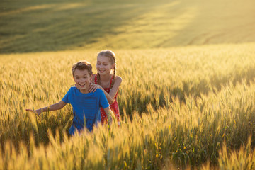 Naklejka na ściany i meble boy and girl are in the middle of a yellow wheat field, laughing and having fun, gestures and emotions, the concept of lifestyle