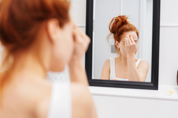 Fototapeta premium Young woman reflected in a bathroom mirror