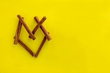 cinnamon sticks isolated on yellow background. sticks in the shape of a heart.