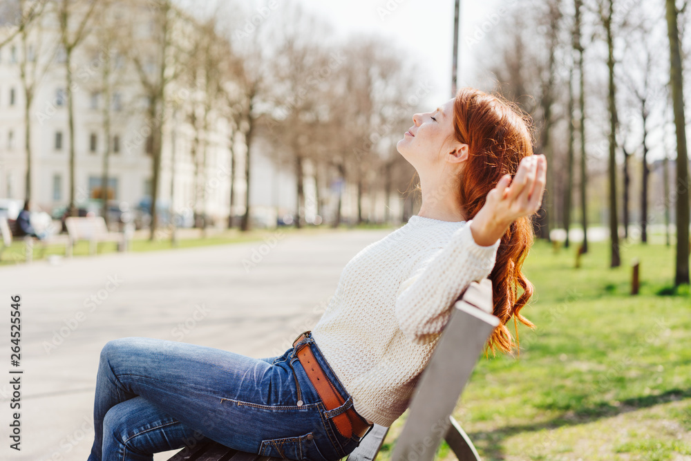 Wall mural Woman on bench enjoying warm spring day