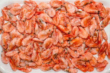 Raw shrimp background. Pile of frozen shrimps on white background.Close-up of frozen shrimps. Shrimp and ice, top view.
