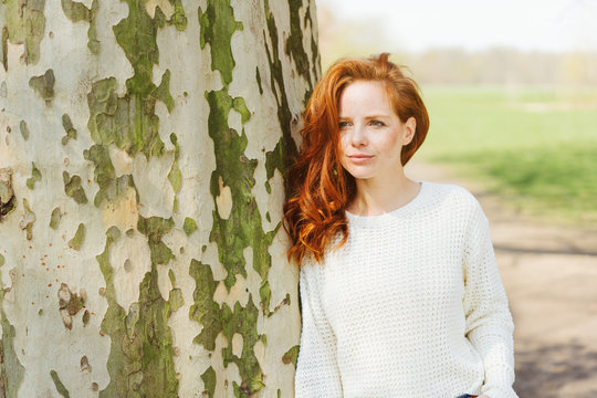 Thoughtful young redhead woman in a park
