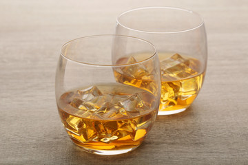 Two glasses with whiskey with ice cubes