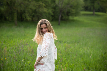 Fototapeta na wymiar Young happy caucasian woman smiling in a meadow full of flowers. Nature and happiness concepts