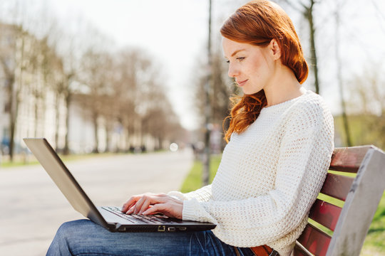 Woman using laptop for work in park