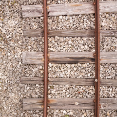 Fototapeta na wymiar Old rusty rails on wooden sleepers sprinkled with small stones. Top view of the vintage railway tracks. Closeup