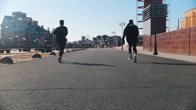 Urban streets. Two men running on the street and synchronously making tricks