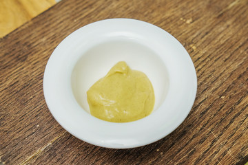 Mustard in a white Cup on a cutting Board