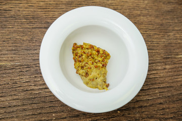 Mustard in a white Cup on a cutting Board