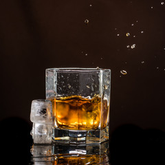 hexagonal glass of whiskey with ice on a dark background and a number of real ice cubes
