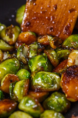 young woman fries Brussels sprouts on a frying pan