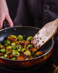young woman fries Brussels sprouts on a frying pan