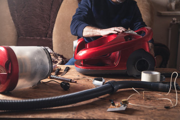 Man repairs of vacuum cleaner. Repairing - obrazy, fototapety, plakaty