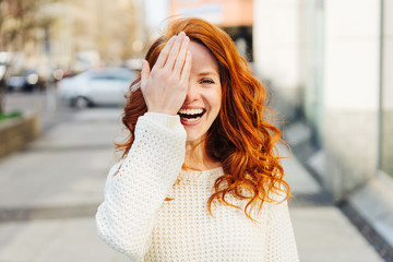 Laughing playful young woman covering one eye