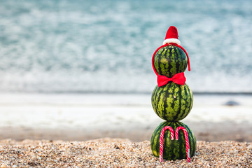 summer snowman of watermelons with Christmas candy in red bow tie and Santa hat.