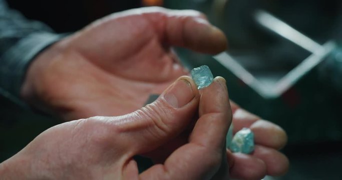 Slow motion of experienced goldsmith sorting high quality aquamarine stones, selecting them to make precious jewels in workshop. Shot in 8K. Concept of jewelry, luxury, goldsmith, diamonds,brilliance