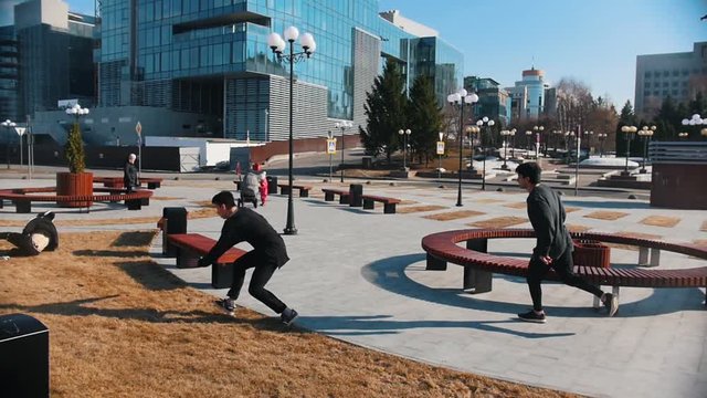 Urban streets. Three men running in the park and overcoming benches