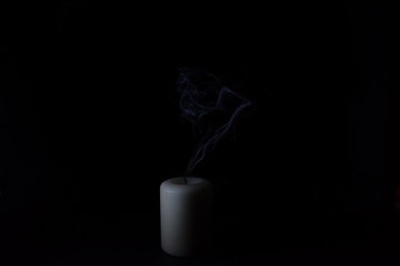 Blue smoke from an extinguished candle on a black background