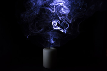 Blue smoke from an extinguished candle on a black background