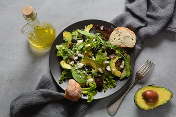 Avocado salad with lettuce, blackberry, blue cheese, olive oil and arugula on a plate. Healthy vegan food concept