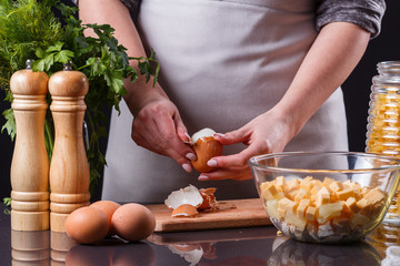 young woman in a gray apron cleans the boiled egg
