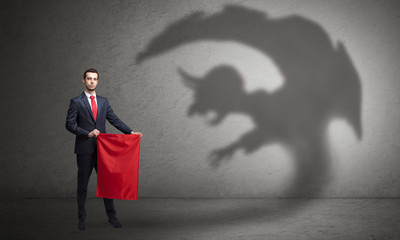 Businessman standing with red cloth in his hand and imp shadow on the background
