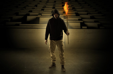 Ugly, aberrant man coming out from the labyrinth with burning flambeau on his hand
