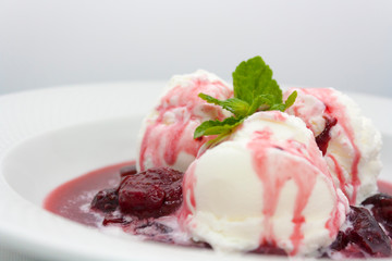 three scoops of delicious ice cream with flowing plum jam and a sprig of mint luxury class on a white background in the restaurant