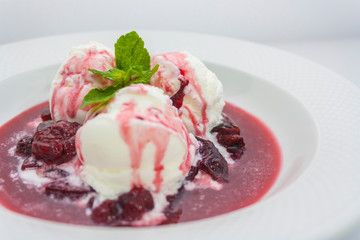 three scoops of delicious ice cream with flowing plum jam and a sprig of mint luxury class on a white background in the restaurant